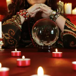 A person gazing into a crystal ball surrounded by candles.